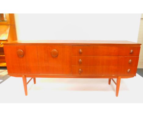 A vintage teak sideboard, with button and nasal shaped handles, with three long drawers flanked to the left by a cupboard doo