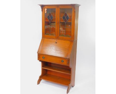 A Victorian oak Arts and Craft style bureau bookcase, the pediment over a pair of stained glass panelled doors, opening to re