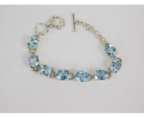 A silver and blue topaz eight stone bracelet, on a ring and t bar fittings, 32ct, with certificate.