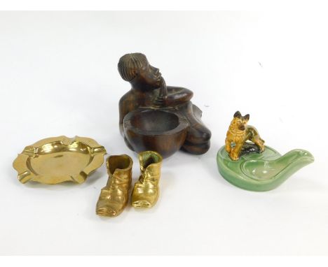 A group of ashtrays, including a carved tribal wooden ashtray with a figure enveloping the bowl, two boot ashtrays and anothe