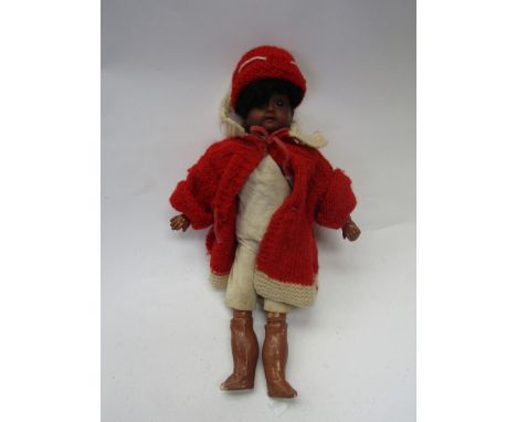 An early 20th Century Black bisque head girl doll on jointed composition body in chamois shirt and breeches and knitted red c