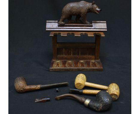 An early 20th century German Blackforest pipe rack, carved with a bear to the top, together with 4 pipes.