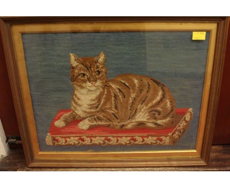 An early 20th century tapestry portrait of a recumbent cat posing on a cushion, glazed and framed, 34x45cm