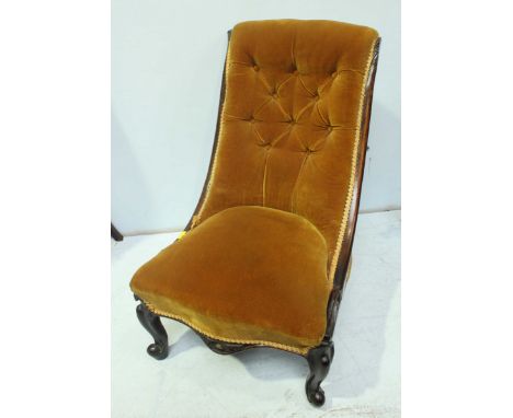 A Victorian carved mahogany low nursing chair, with gold coloured button back upholstery and supported on carved cabriole leg