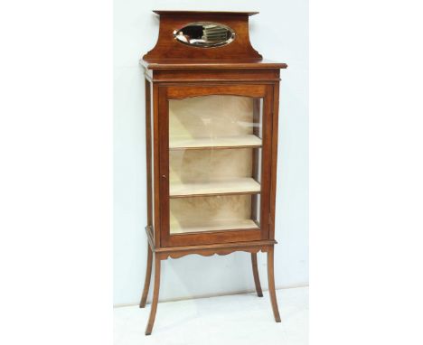 An Edwardian mahogany display cabinet, the top with oval bevelled mirror, and single glazed door supported on curved legs. 61