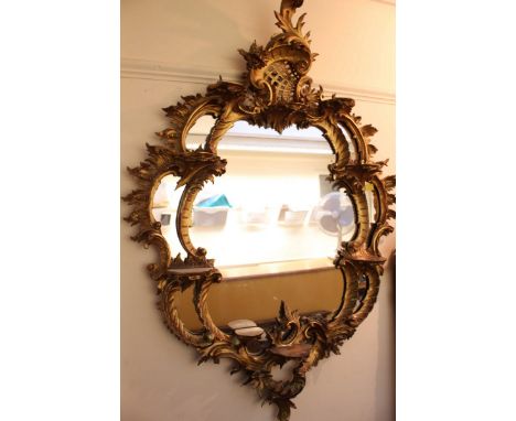 A large early 20th century carved giltwood and gesso Rococo style wall mirror, with ornately carved and shaped frame with int