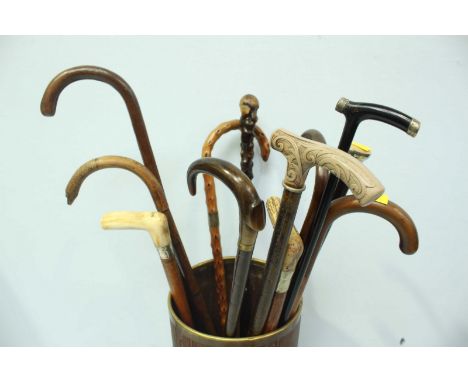 A brass walking stick stand, together with a quantity of assorted walking sticks, including a fine ebonised and silver capped