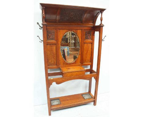 An unusual Victorian carved oak hall stand with concave floral carved panel to the top, oval mirror above lidded storage comp