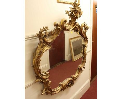 A large 18th century style Rococo gilt gesso wall mirror, with ornately scrolled foliate frame, crested with a cornucopia of 