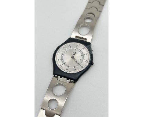 An AG 1999 Swatch watch with black plastic case and stainless steel strap. With original box and paperwork. Plastic film cove