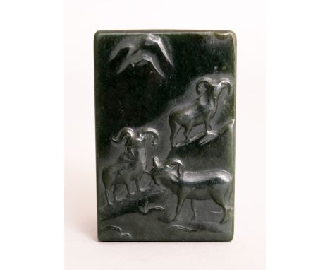 A CHINESE DARK GREEN JADE TABLET, the top surface carved with three rams on a rocky slope, 2.1in x 1.3in.