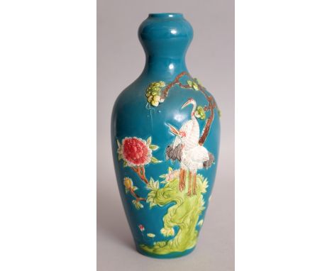 A CHINESE BLUE GROUND FAMILLE ROSE MOULDED PORCELAIN VASE, decorated in shallow relief with a pair of storks perched on rockw