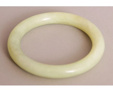 A CHINESE CELADON JADE BANGLE, 3.25in diameter, the inner rim 2.3in diameter.