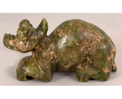 A 20TH CENTURY CHINESE GREEN JADE MODEL OF A MYTHICAL BEAST, the crouching animal with large eyes, the stone with russet incl