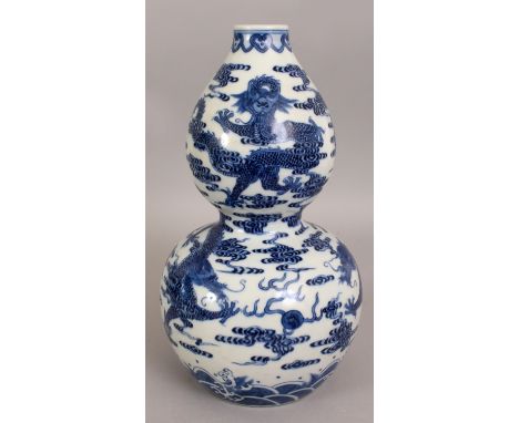 A CHINESE BLUE & WHITE DOUBLE GOURD PORCELAIN DRAGON VASE, decorated with dragons amidst cloud scrolls, the base with a drill