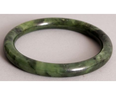 A CHINESE SPINACH GREEN JADE BANGLE, 3.25in diameter, the inner rim 2.4in diameter.