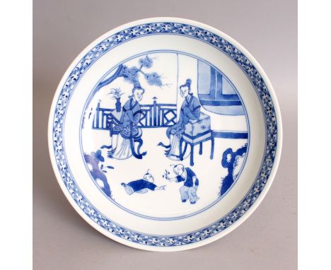 A CHINESE BLUE & WHITE PORCELAIN SAUCER DISH, the interior decorated with a garden terrace scene of conversing ladies and pla