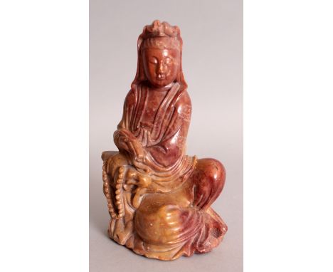 A 19TH/20TH CENTURY CHINESE SOAPSTONE FIGURE OF GUANYIN, reclining against a rockwork plinth and holding a scroll, 6in high.