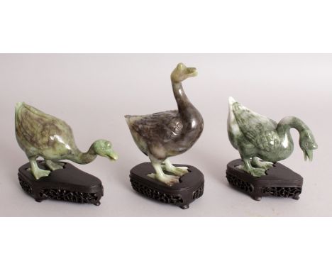 A SET OF THREE 20TH CENTURY JADE LIKE HARDSTONE GEESE, each with a fitted wood stand, each stone of predominantly green hue w