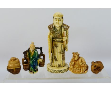 Two carved tagua nut netsuke, one in the form of a coiled snake, the other a ram, carved bone okimono of a gentleman, 16 cm (