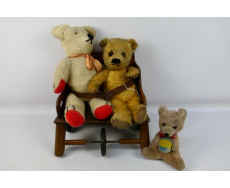 Three unmarked vintage teddy bears sitting on a vintage 'Little Buffer' children's mobile chair. Bears include a gold mohair 