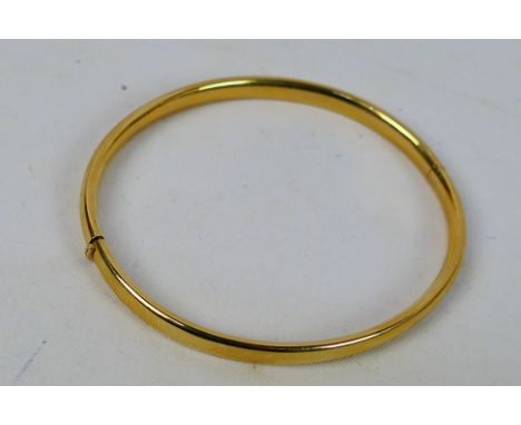 A yellow metal hinged bangle, stamped 585, approximately 7.4 grams. [W]