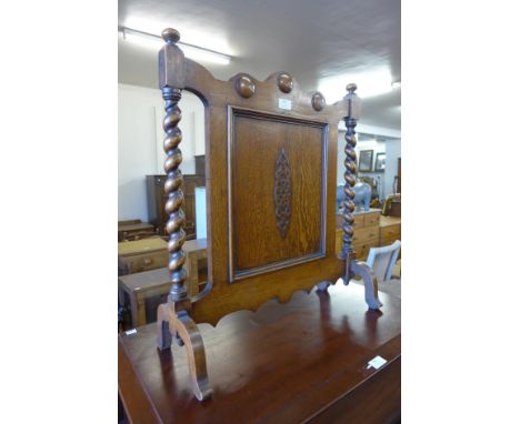 A carved oak barleytwist fire screen 