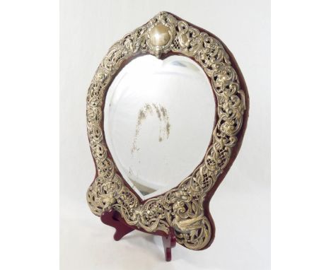 An early 20th century Continental heart-shaped bevelled edge dressing table mirror, within ornate pierced and embossed surrou