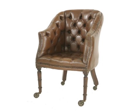 A leather button-back desk chair, raised on ring turned front legs and oversize castors
