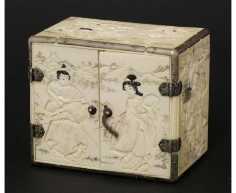 A Japanese ivory miniature cabinet, c.1880-1900, each panel carved in low relief with figures, silver mounted, opening to rev