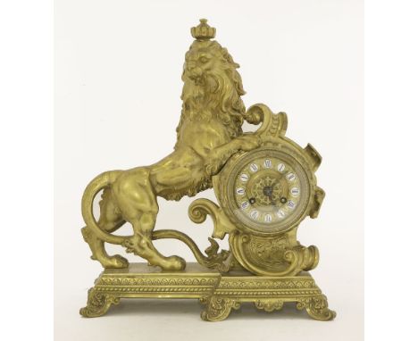 A French gilt mantel clock, the dial with enamelled numerals, mounted with a lion to the side,33.5cm high