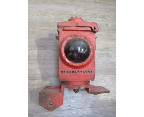 A red painted signal lamp case, mounted for level crossing gates