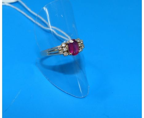 A modern dress ring set with a central ruby flanked by 5 small diamonds to either shoulder, 3.4 gm