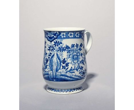 A large Bow blue and white mug, c.1760, the generous bell shape painted with flowering peony sprays flanking rockwork, the ri