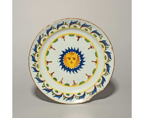 A rare delftware plate, c.1760-70, probably Bristol, painted in blue, green, red and yellow with a central sun with a face, t