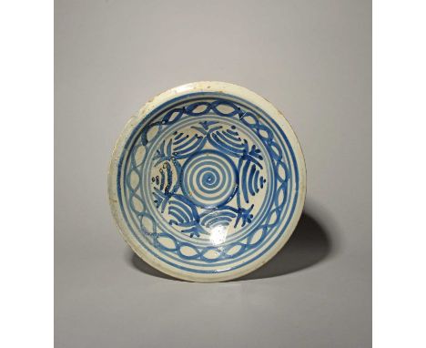 A delftware charger, c.1700, of deep shape, painted in blue with a geometric design of a central spiral within concentric cir