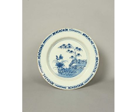 A large Bristol delftware charger, c.1740, painted in blue with flowering lotus before an ornamental fence and leafy bamboo, 