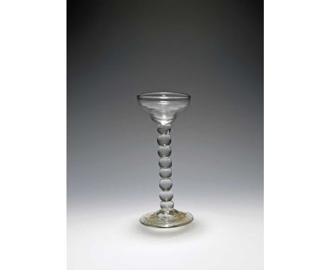 A rare sweetmeat glass, c.1720, the shallow ogee bowl raised on a bobbin knop stem with eight consecutive ball knops, over a 