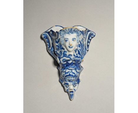 A delftware wall pocket, mid 18th century, moulded with a female mask to the top within leaf and shell scrolls, the base with