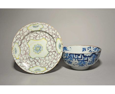 A large delftware punch bowl, c.1770, painted in blue with formal foliate scrolls, and a delftware charger, painted in blue, 