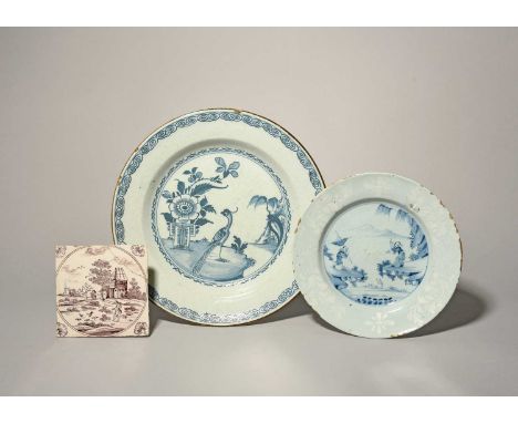 A delftware plate, c.1760, painted in blue with two Chinese figures communicating between rocky ledges, the rim with a bianco