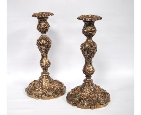 Pair of silver Georgian candlesticks with floral and scroll embossed columns on circular bases, John Wilkinson &amp; Co., She