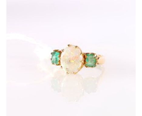 Yellow metal three-stone ring set with central opal flanked by two emeralds.