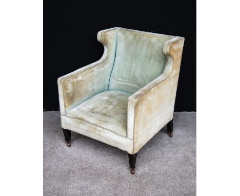 Edwardian upholstered armchair with deep seat and raised on square tapering legs and ceramic castors, 68cm wide, 82cm high an