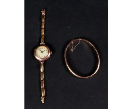 A 9ct rose gold hinged bangle, engraved with scrolling foliage to one side, to a box and tongue clasp and safety chain, 5.9g;