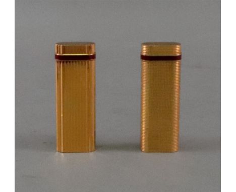 Two Cartier gold plated lighters, each with a red enamel band, one with ribbed sides, no. 99430 S, the other engine turned wi