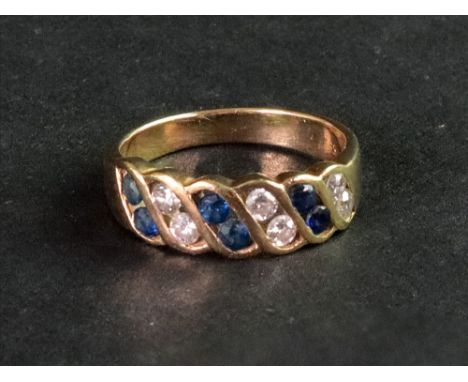 A gold sapphire and diamond set half hoop dress ring of wave scroll design, channel set with alternating circular cut sapphir