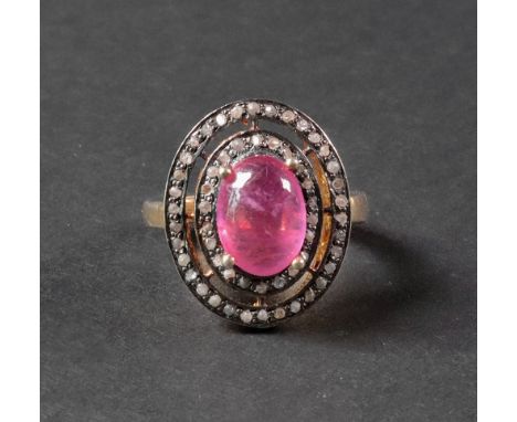 A silver gilt, cabochon ruby and diamond-set dress ring of oval plaque design, set with a cabochon ruby, in a surround of two