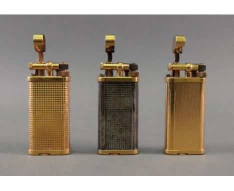 Three Alfred Dunhill lighters, of oval section, one with engine turned front and back, one engine turned with faceted square 
