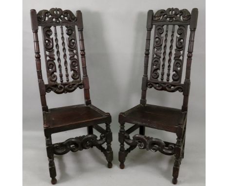 A pair of late 17th century oak side chairs, the high backs with crown, scroll and leaf carved and pierced top rails, the spi